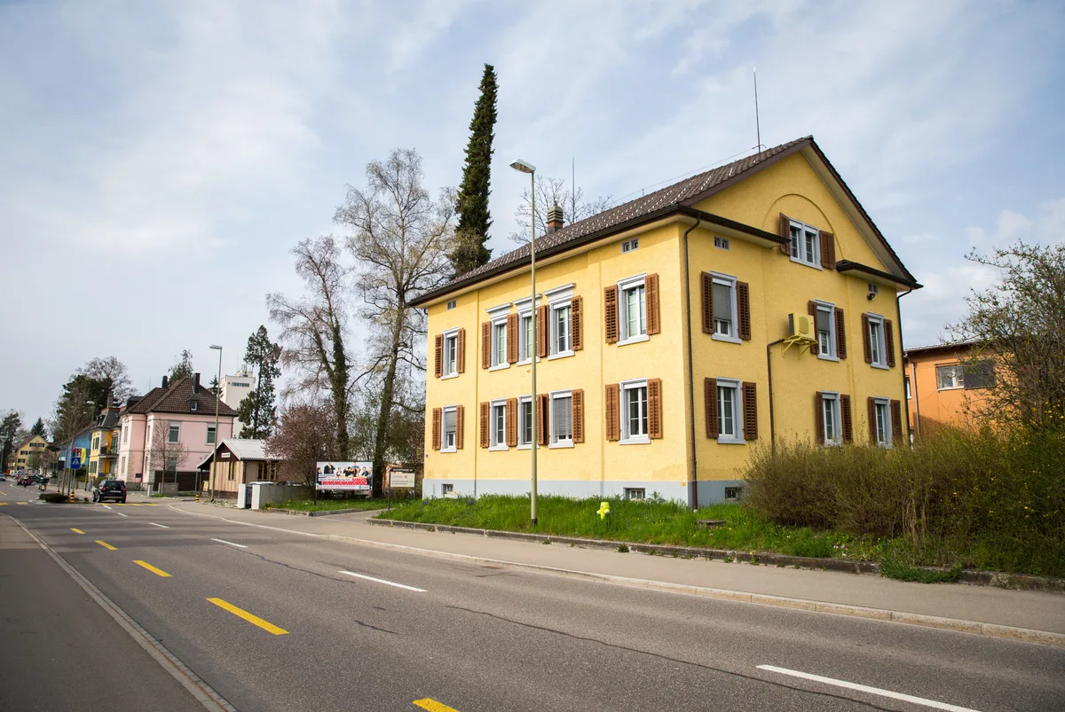 Ein gelbes Haus an einer Strasse.